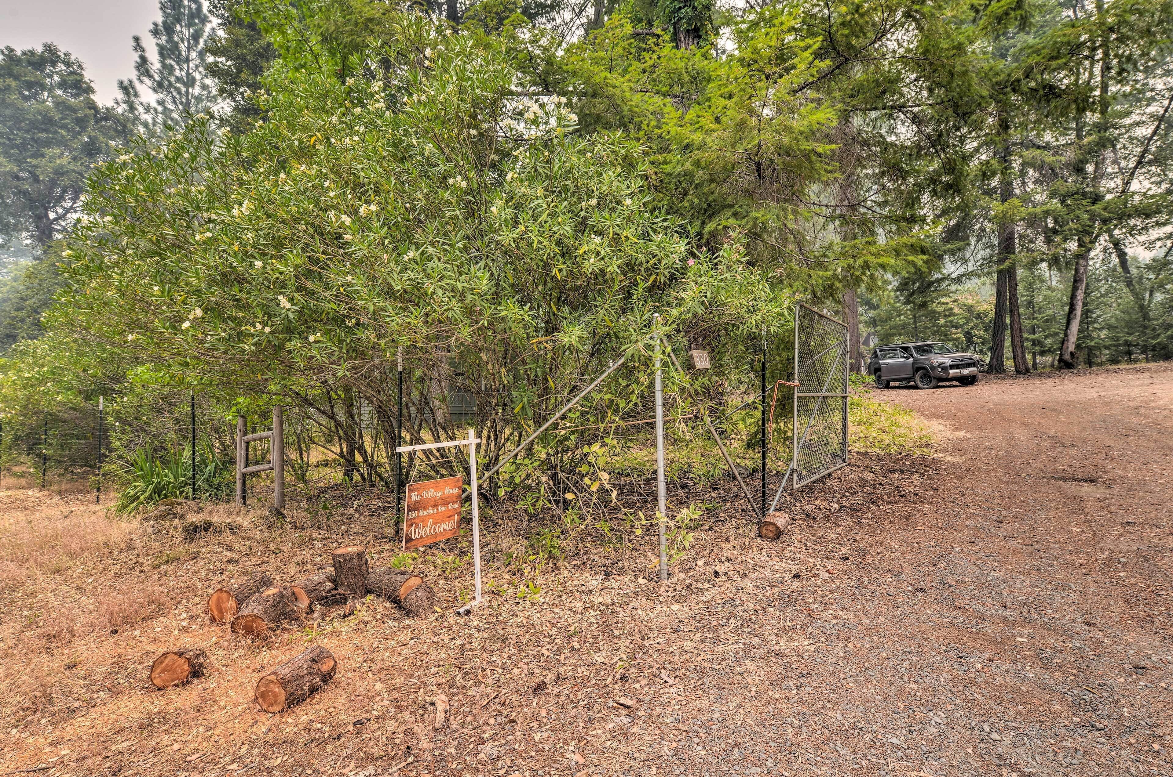 A dirt path leading to a fenced area with a vehicle parked nearby.