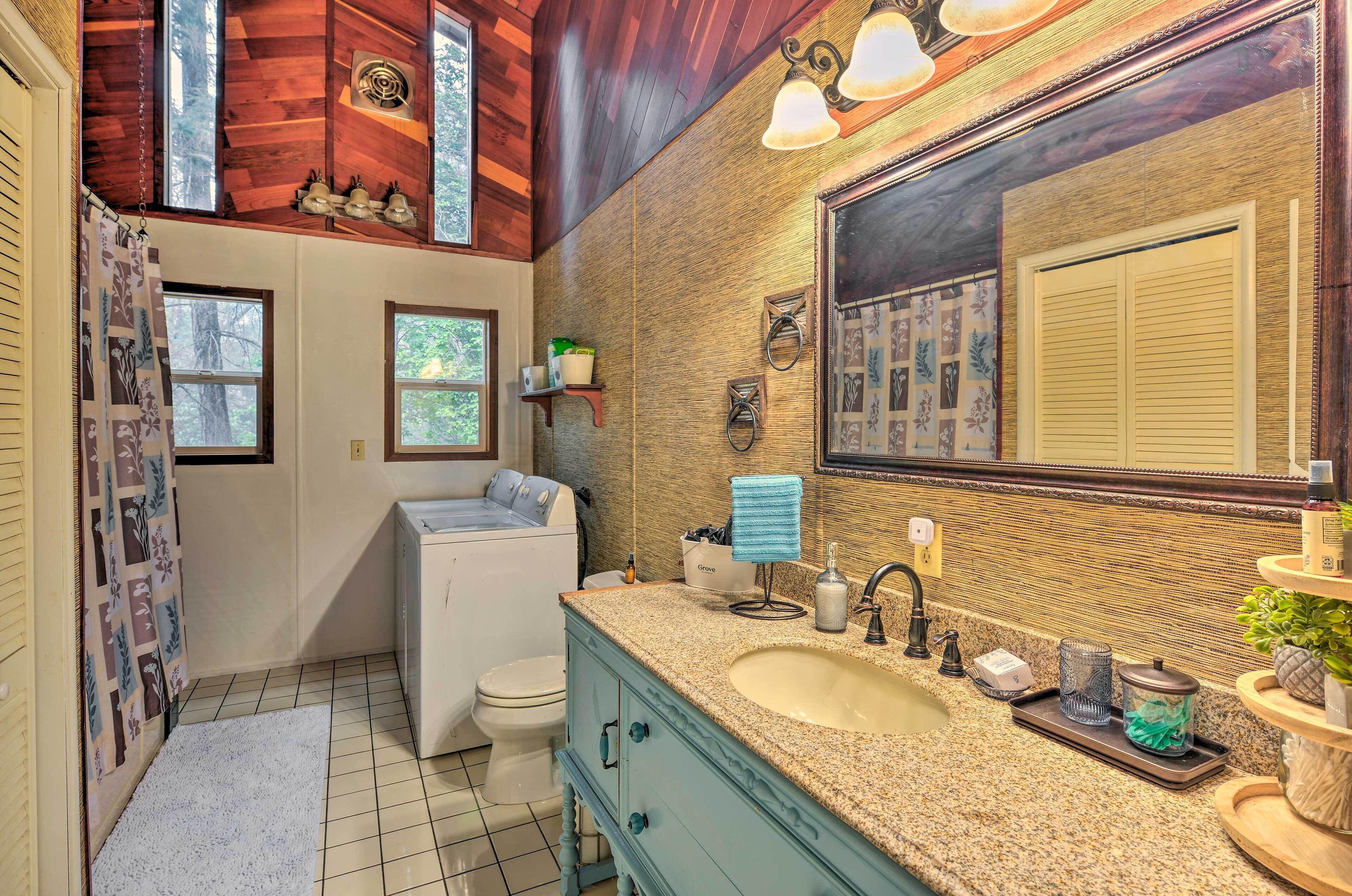 A bathroom with a wooden ceiling, a large mirror, a sink, and a toilet.