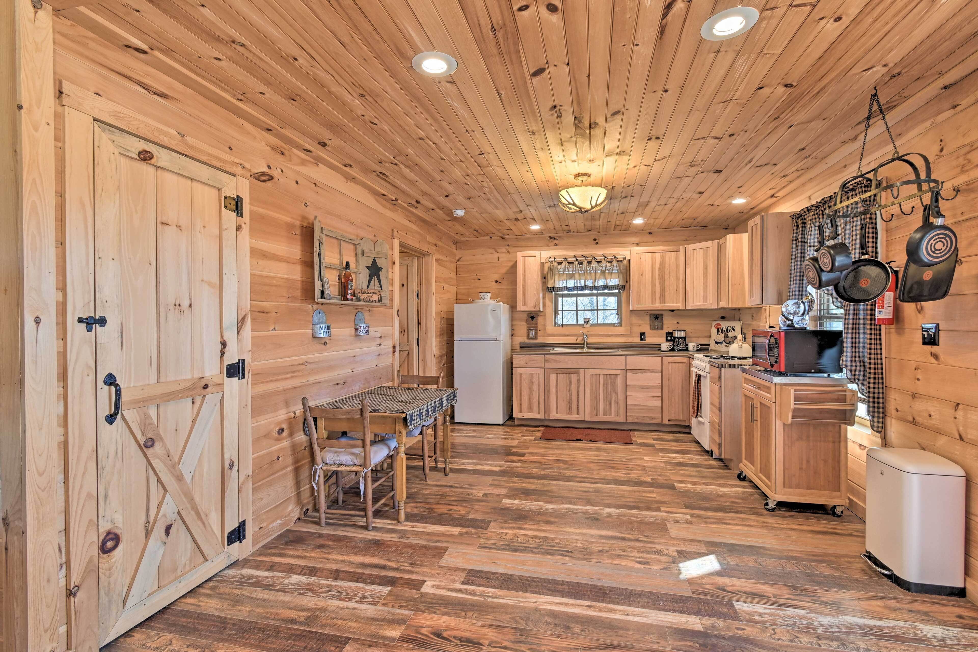 L’intérieur d’une cabane en bois comprend une table à manger, des chaises, un coin cuisine et un réfrigérateur.