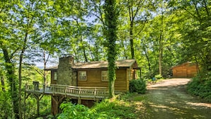 A rustic cabin with a wooden deck and stone chimney, surrounded by lush greenery and a dirt path leading to a wooden gate. - Secluded 'mountain Home' 12 Mi to Tsali Area (Robbinsville)