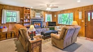 A cozy living room with a fireplace, comfortable seating, a television, and a bookshelf. - Secluded 'mountain Home' 12 Mi to Tsali Area (Robbinsville)