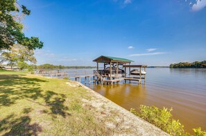 A wooden dock extending into a calm lake, with a covered seating area and a grassy bank. - 'the Whacky Shack' Family Cabin w/ Fire Pit! (Trinity)