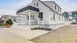 A two-story house with a covered porch, a small garden, and a gravel driveway. - Sunset & Water Views in WWC on Sunset Lake (Wildwood Crest)