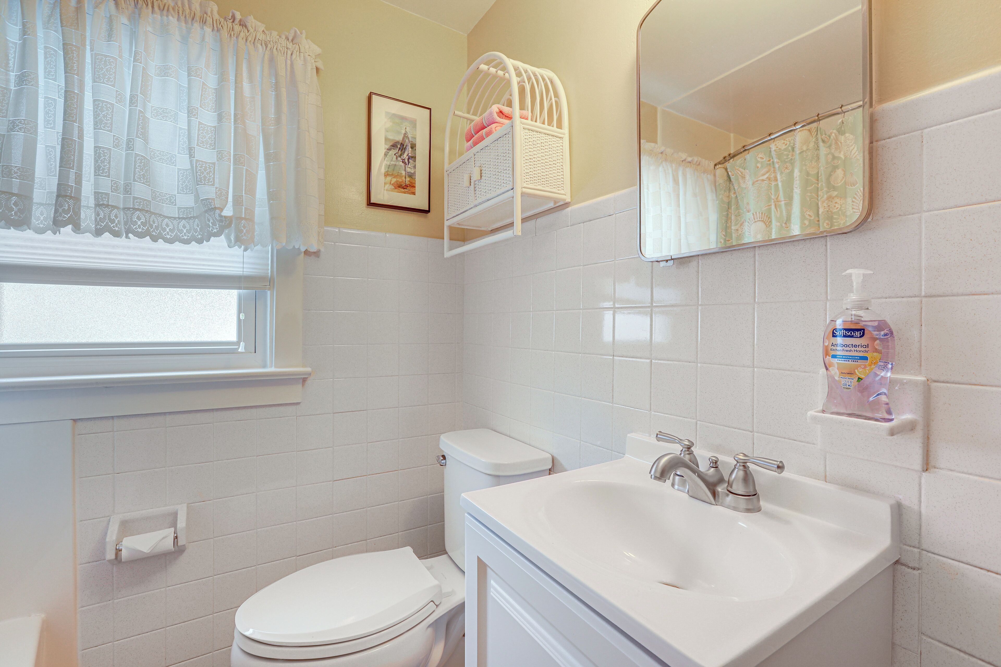 A bathroom with a toilet, sink, and a window with a curtain.