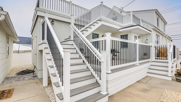 A two-story house with a white exterior, a covered porch, and a staircase with white railings. - Sunset & Water Views in WWC on Sunset Lake (Wildwood Crest)