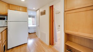 A kitchen with wooden cabinets, a white refrigerator, and a microwave. - Winery Cabin in Fredericksburg w/ Wraparound Deck! (Fredericksburg)