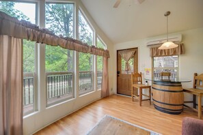 A room with large windows, a wooden barrel table, and a ceiling fan. - Winery Cabin in Fredericksburg w/ Wraparound Deck! (Fredericksburg)