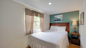 A bedroom with a bed, a nightstand, a lamp, and a painting on the wall. - Winery Cabin in Fredericksburg w/ Wraparound Deck! (Fredericksburg)