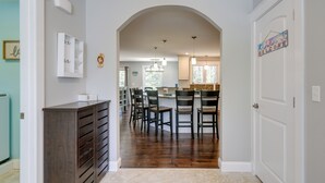 Een gang die uitkomt in een keuken met een eethoek, met een houten kast, stoelen en een welkomstbord.