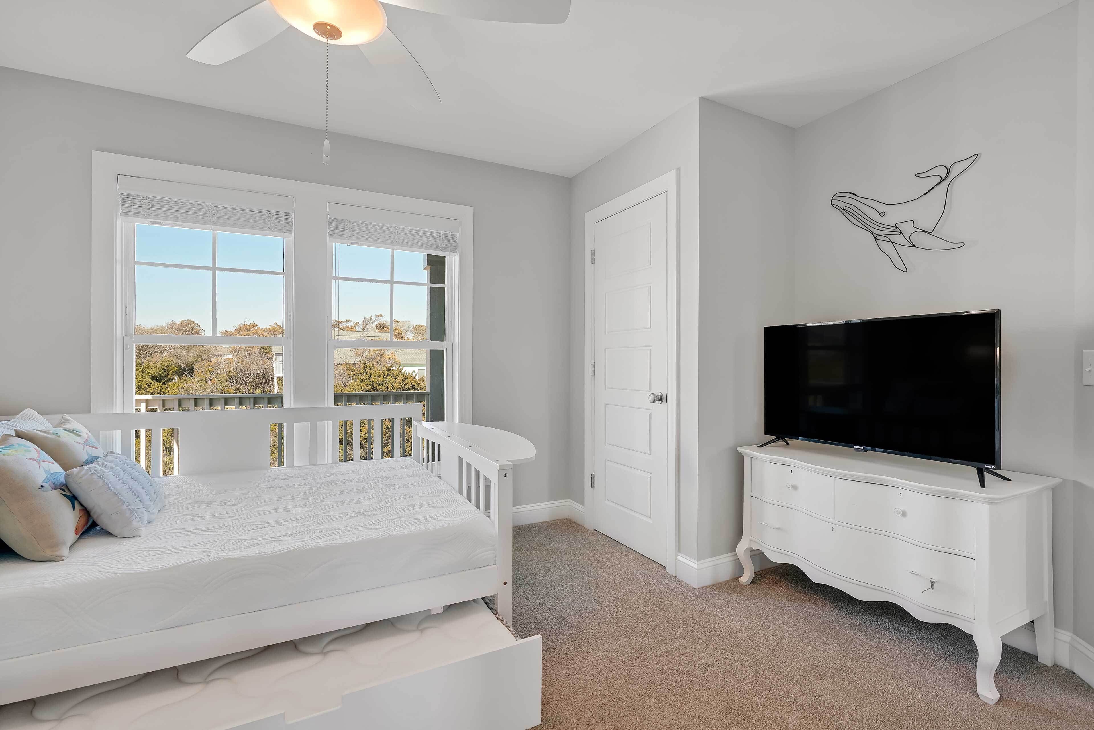 A bedroom with a bed, a TV, a dresser, and a balcony.