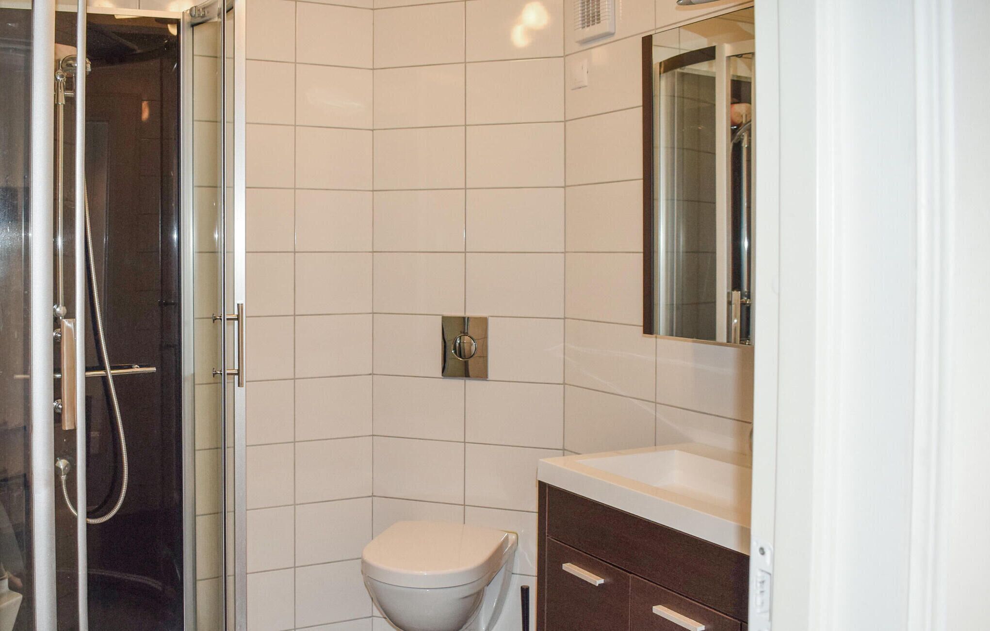 Une salle de bain comprenant des toilettes, une douche et un meuble-lavabo avec un miroir.