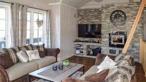 Ein gemütliches Wohnzimmer mit Kamin, einer Couch, einem Couchtisch und einem Fernseher.