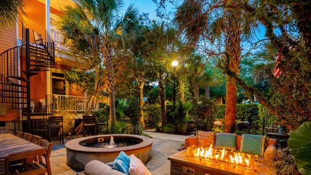 A patio with a fire pit, outdoor seating, and a staircase leading to an upper level.