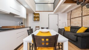A modern living space with a dining area, kitchen, and a loft bedroom. - Castello Loft Heaven (Cagliari)