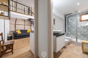 A modern interior with a loft-style living area, a kitchen with a large island, and a shower with a glass enclosure. - Castello Loft Heaven (Cagliari)