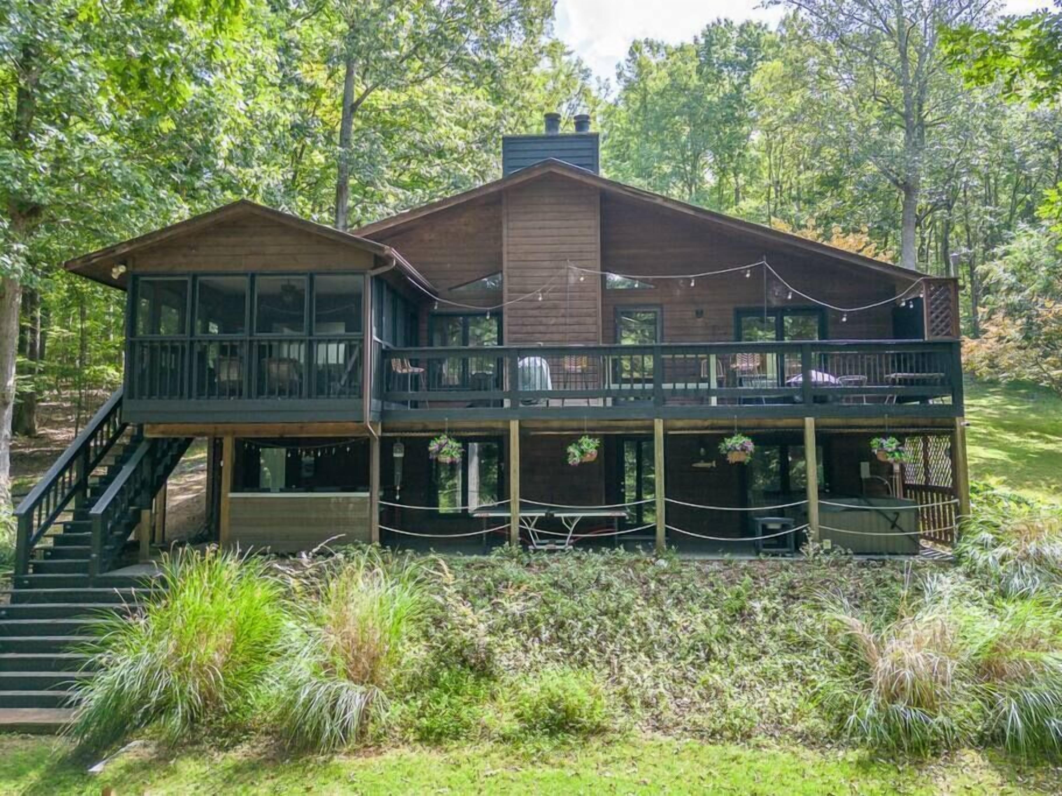 Une cabane en bois à deux étages, dotée d’un balcon et entourée d’une végétation luxuriante.