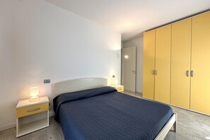A bedroom with a bed, bedside tables, a wardrobe, and a mirror.