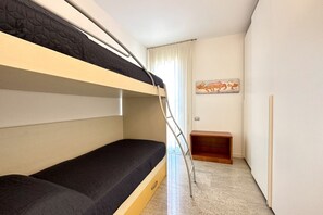 Une chambre avec un lit superposé, une échelle, une petite étagère en bois et un tableau accroché au mur.