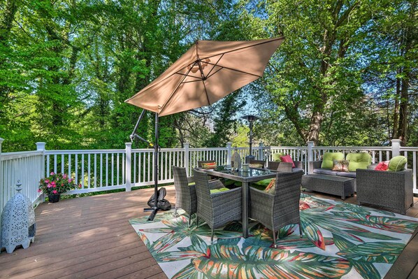 A deck with wicker furniture, a table, and a large umbrella. - Adorable Beach Cottage w/ Hot Tub & Tropical Bar! (Chesapeake Beach)