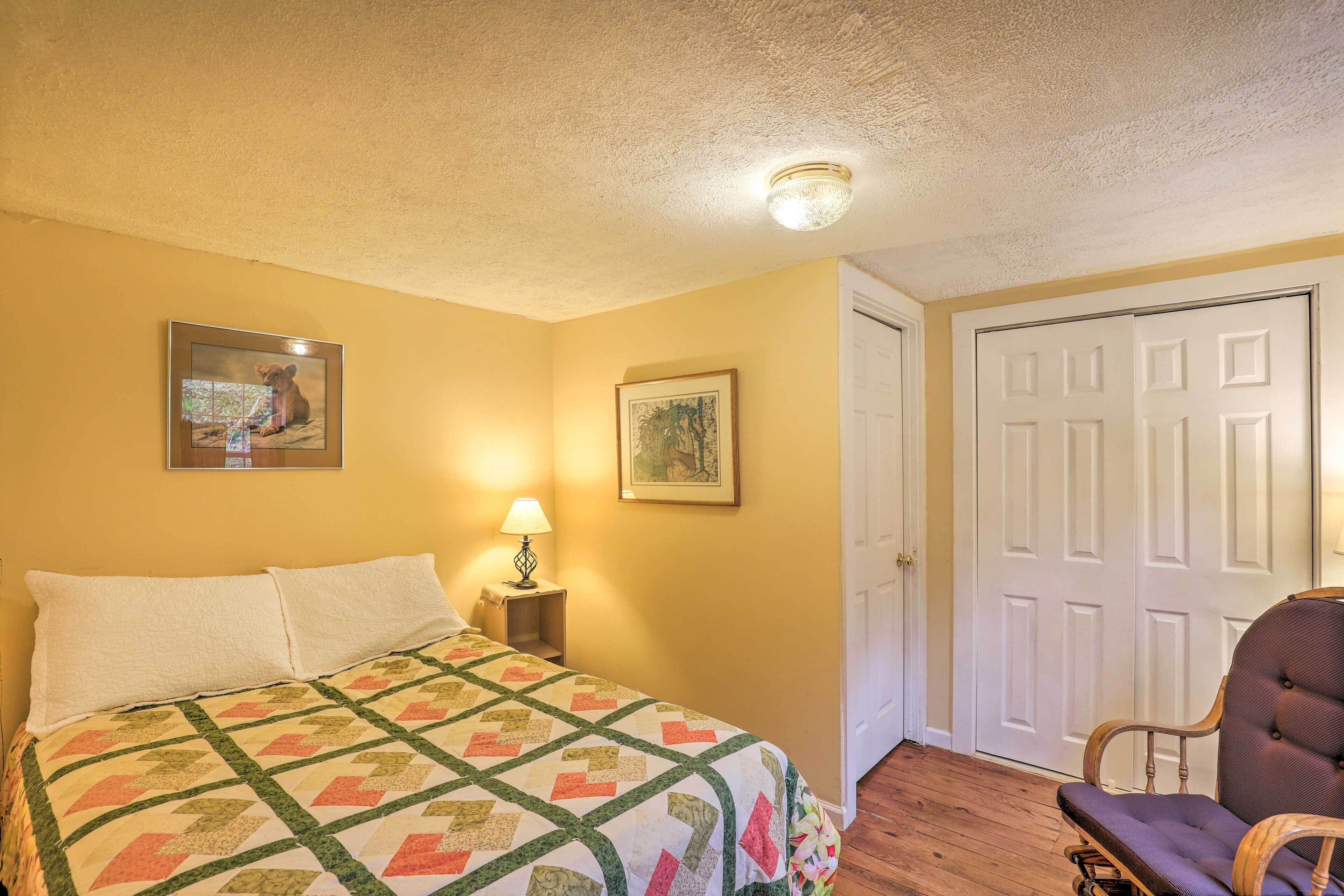 A bedroom with a bed, a chair, a door, and two framed pictures on the wall.