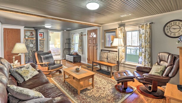 A spacious living room with a leather sofa, a wooden coffee table, and a massage chair. - 'carefree Cottage' < 6 Mi to Downtown Asheville! (Asheville)