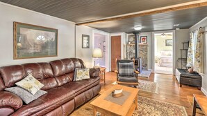A living room with a brown leather sofa, a wooden coffee table, and a fireplace. - 'carefree Cottage' < 6 Mi to Downtown Asheville! (Asheville)