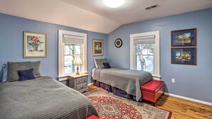 A bedroom with two beds, a red bench, a patterned rug, and framed pictures on the walls. - 'carefree Cottage' < 6 Mi to Downtown Asheville! (Asheville)