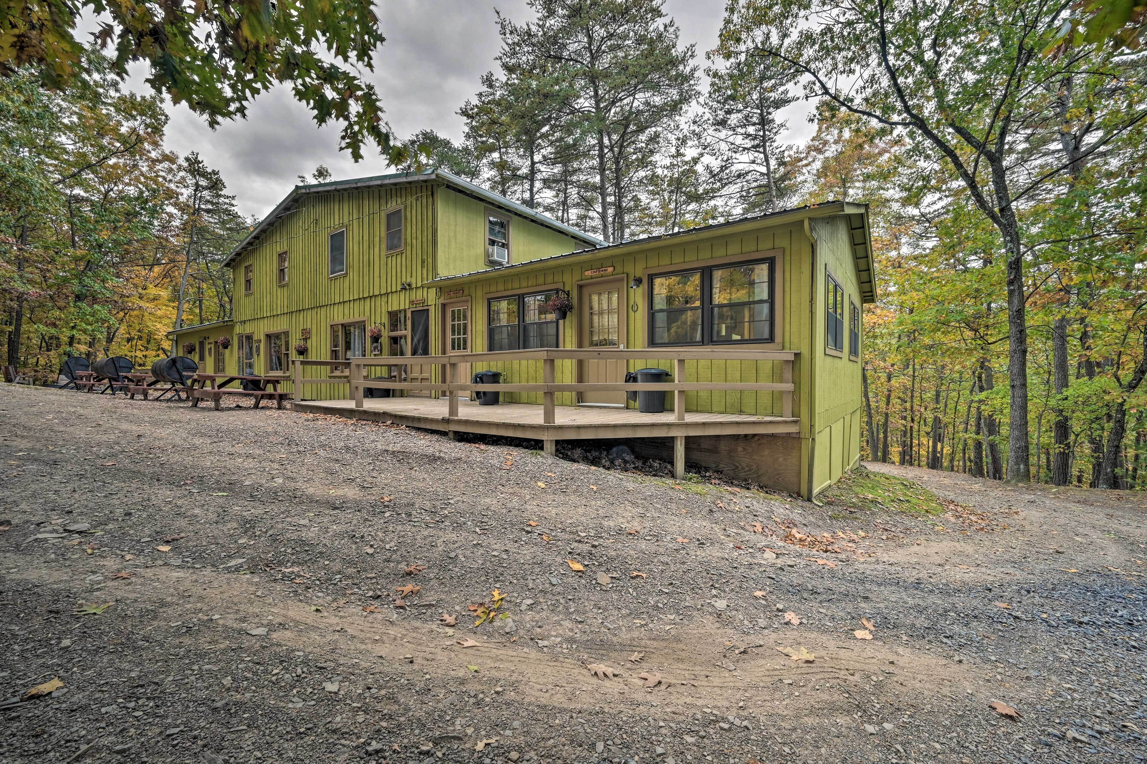 A rustic lodge with a wooden deck and a dirt path leading to it.
