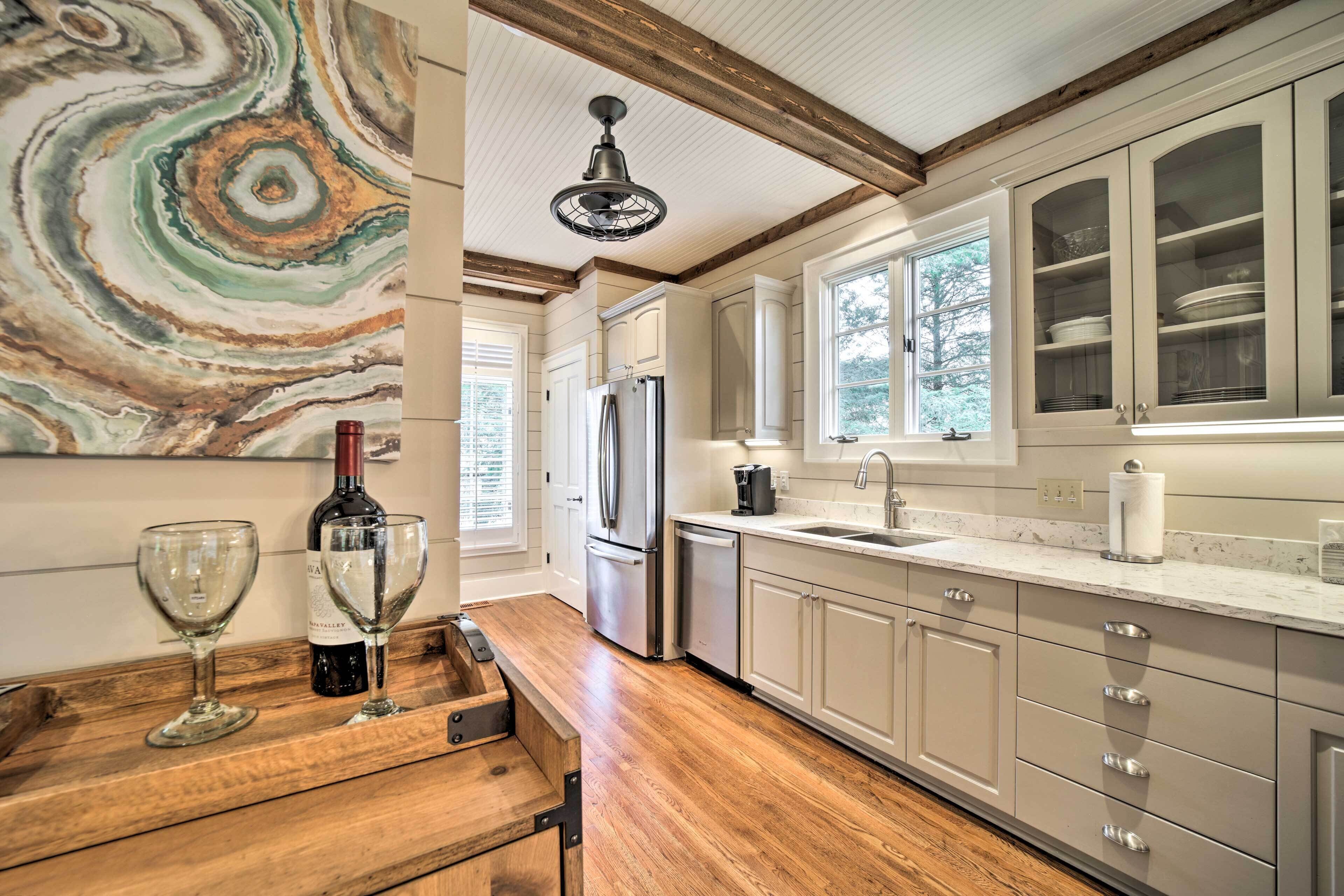A kitchen with wooden flooring, white cabinets, a stainless steel refrigerator, and a marble backsplash.