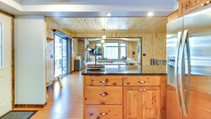 Eine moderne Küche mit Holzausstattung, einem Edelstahlkühlschrank und einer großen Kücheninsel mit Spüle.