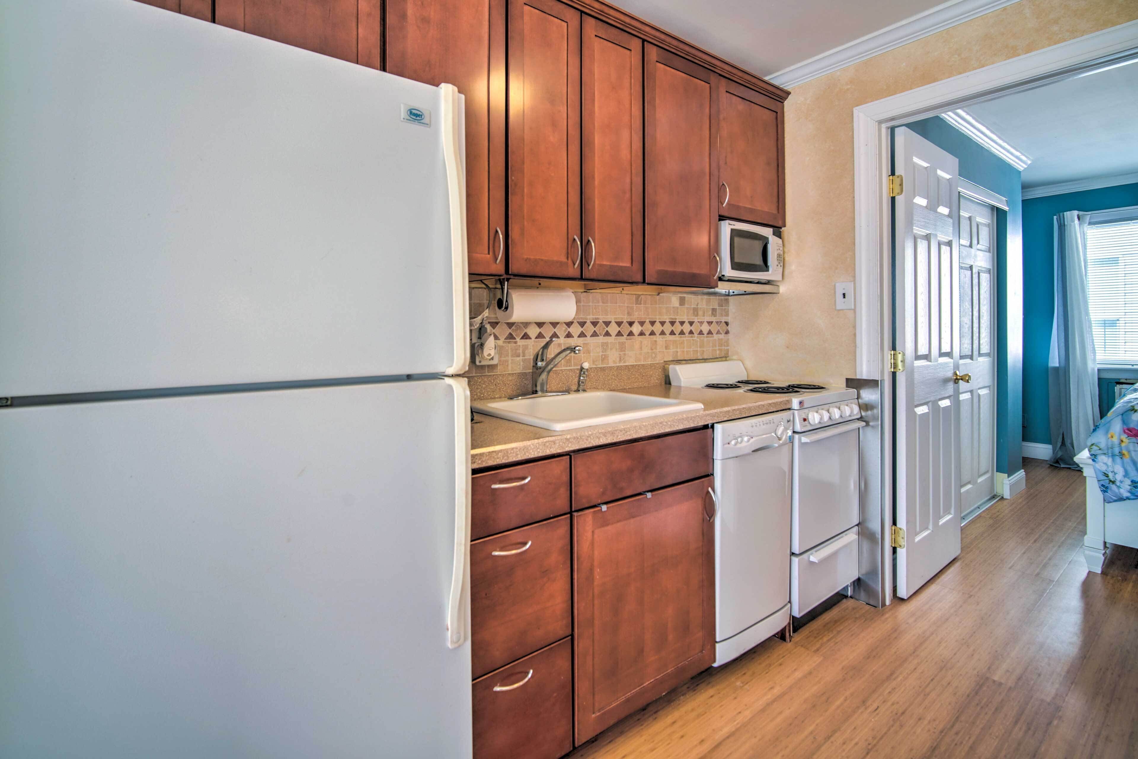 A kitchen with wooden cabinets, a white refrigerator, a microwave, a sink, and a stove.