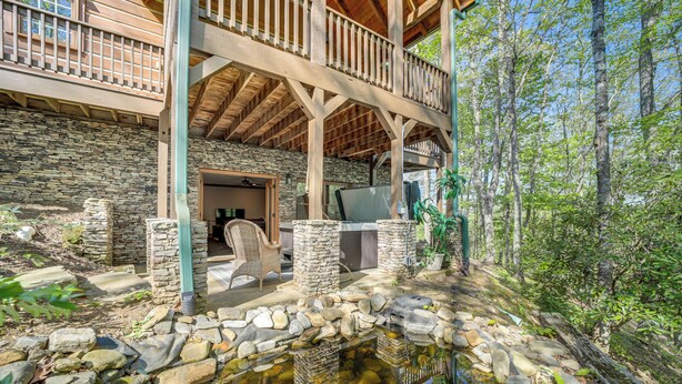 A stone building with a wooden deck and a pond.