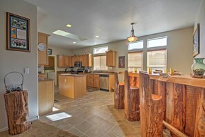 A spacious kitchen with wooden cabinets, a central island, and a rustic wooden bar. - Beautiful Kanab Home w/ Yard - Walk to Restaurants (Kanab)
