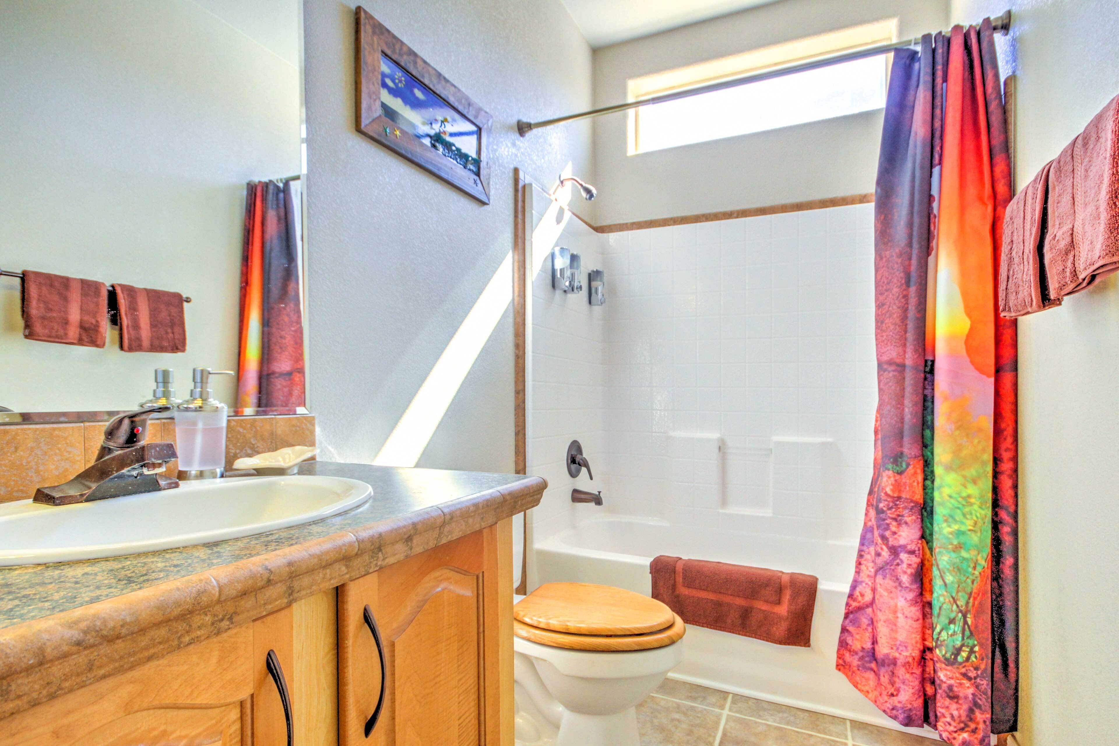 Ein Badezimmer mit Dusche, Toilette, Waschbecken und Fenster.