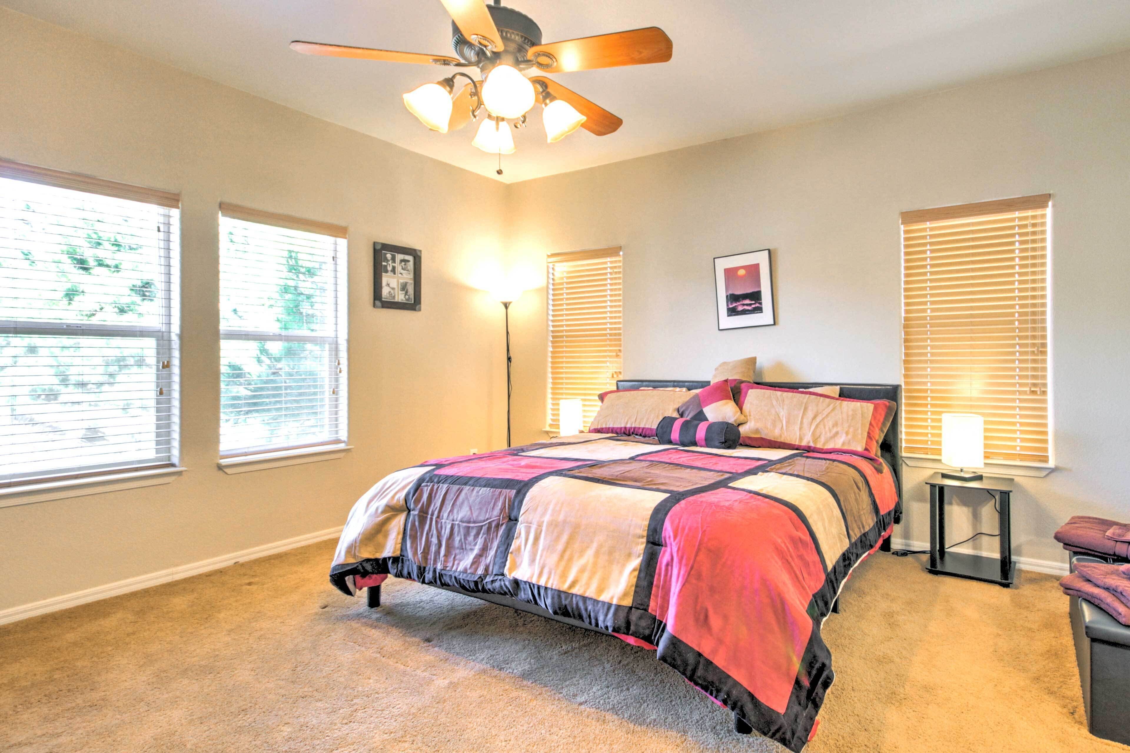 A bedroom with a bed, a ceiling fan, a nightstand, and a window with blinds.