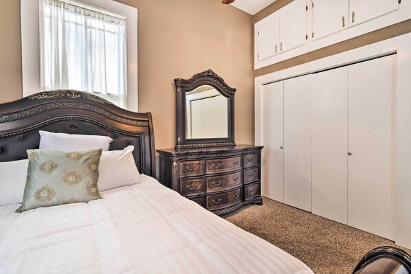 A bedroom with a large bed, a dresser with drawers, a mirror, and a wardrobe.