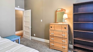 Ein Schlafzimmer mit Bett, Kommode, Spiegel und Kleiderschrank.