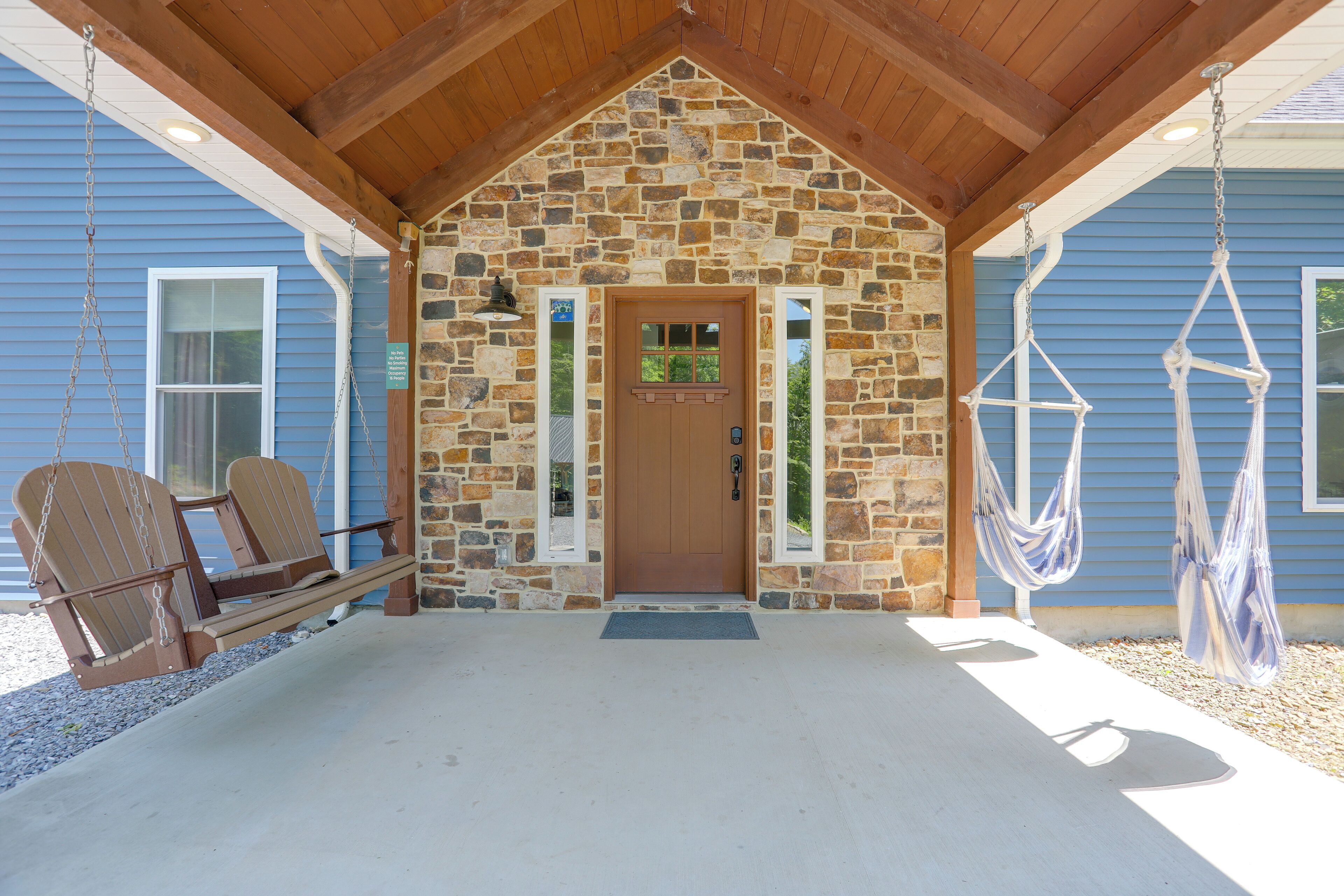 A stone building with a wooden porch, a swing chair, and a hammock.