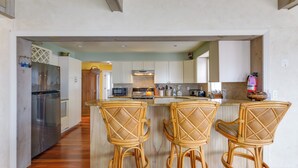 A modern kitchen with a central island, bar stools, and stainless steel appliances. - Delaware Bay & Sunset Views: Cape May Cottage (Cape May Court House)