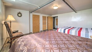 A bedroom with a patterned bedspread, a chair, a lamp, a clock, and a wardrobe. - Ashton Escape w/ Yard: 56 Mi to West Yellowstone! (Ashton)