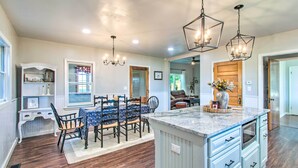 A spacious kitchen with a large island, wooden flooring, and pendant lighting. - Beautifully Restored Farmhouse in Marshall! (Martinsville)