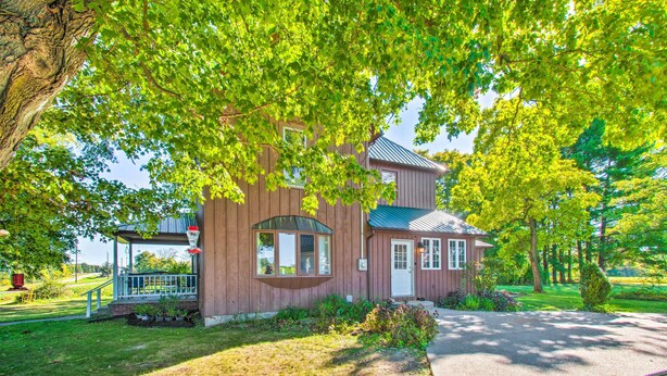 A wooden house with a porch, surrounded by lush green trees. - Beautifully Restored Farmhouse in Marshall! (Martinsville)