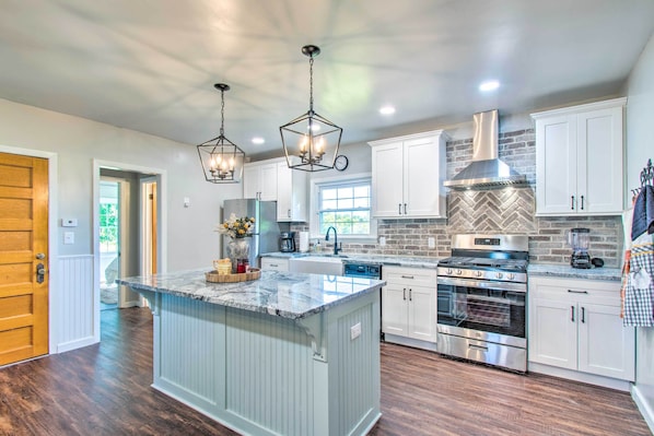 A modern kitchen with a central island, stainless steel appliances, and white cabinetry.