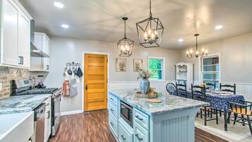 A modern kitchen with white cabinets, a wooden door, and a dining area with a table and chairs.