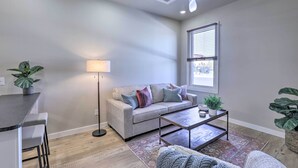 A modern living room with a grey sofa, a coffee table, a floor lamp, and a ceiling fan.