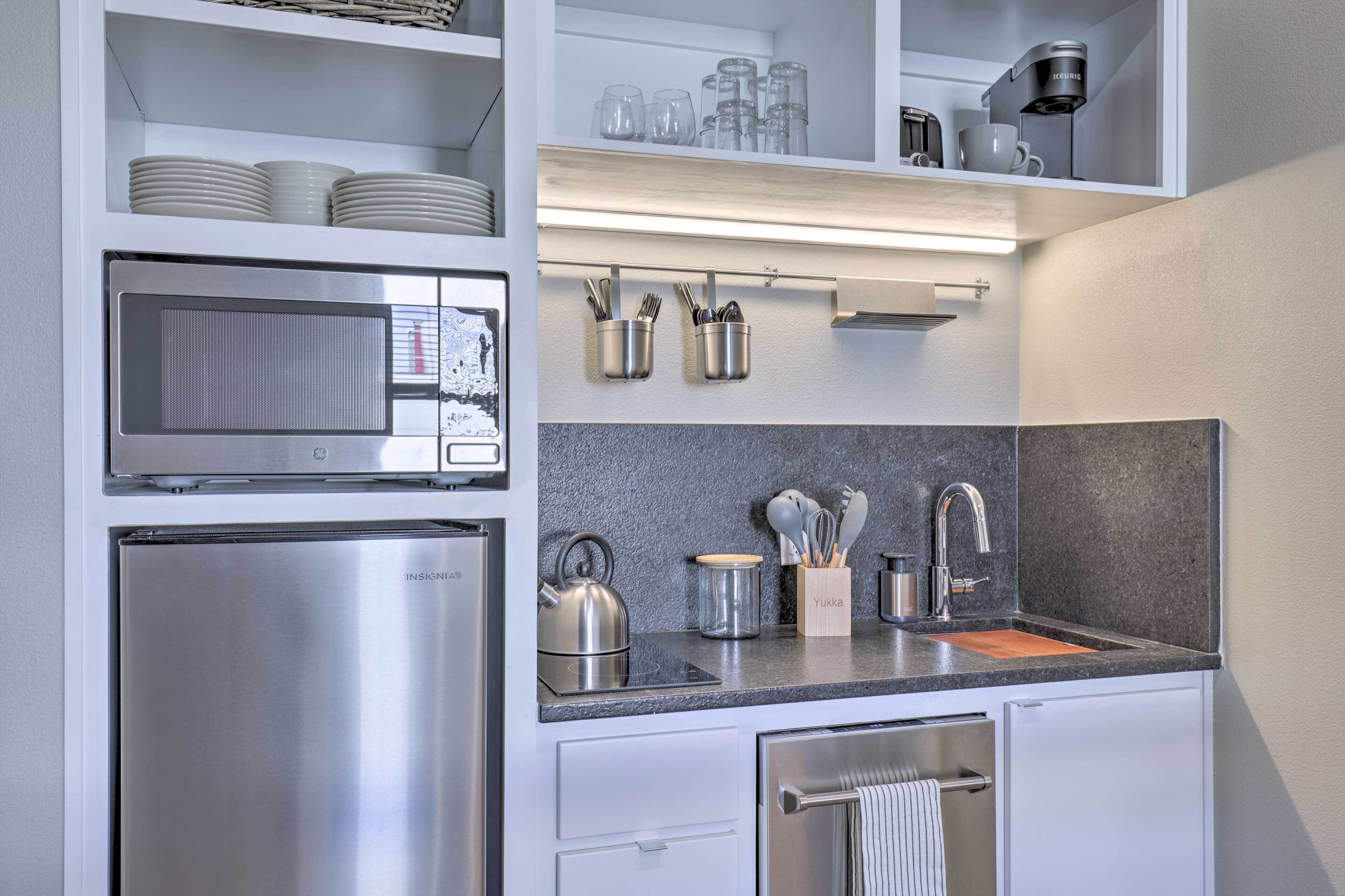 Eine moderne Küche mit eingebauter Mikrowelle, einem Edelstahlkühlschrank und einer Spüle mit Schneidebrett.