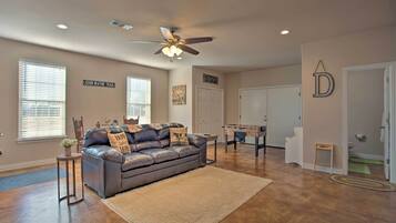 A spacious living room with a leather sofa, a ceiling fan, and a foosball table.