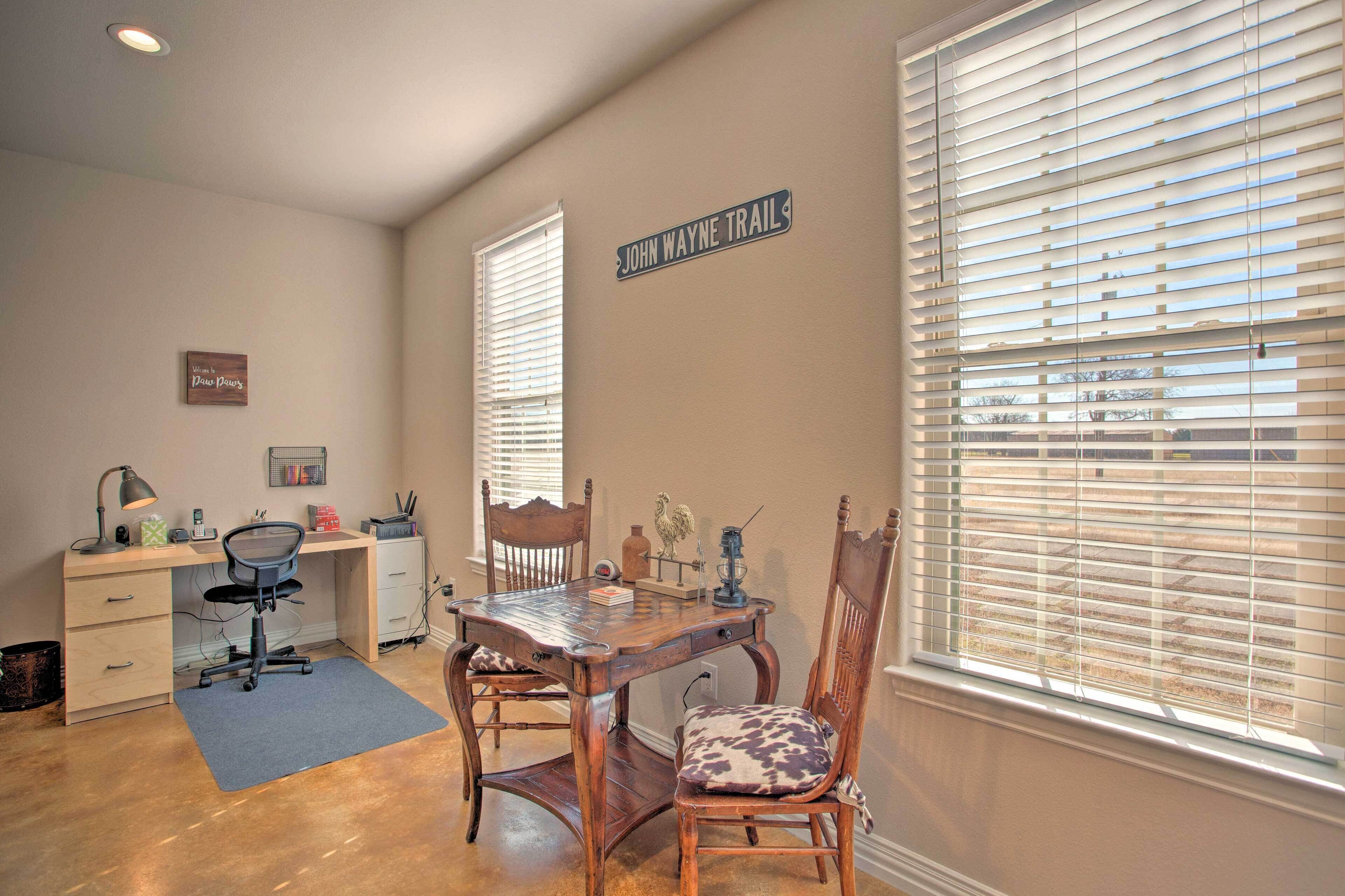 A room with a wooden desk, two chairs, a lamp, and a window with blinds.