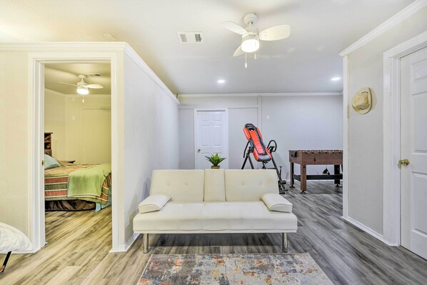 A living room with a white sofa, a ceiling fan, a wooden coffee table, and a futon bed in the background. - Blue Ridge Vacation Rental w/ Game Room! (Blue Ridge)