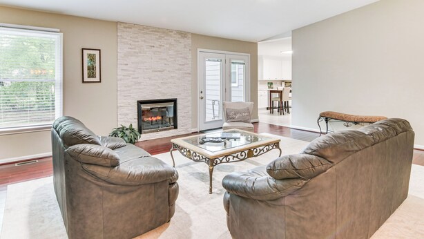 A spacious living room with leather sofas, a glass coffee table, a fireplace, and a view of the dining area. - Charlotte Vacation Rental w/ Private Hot Tub! (Charlotte)